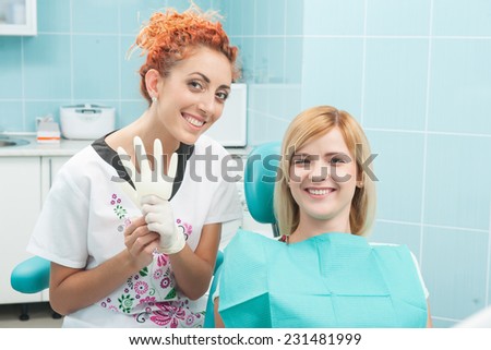 Half-length portrait of young fair-haired lovely smiling girl sitting together with the dentist showing that there is nothing better than healthy teeth