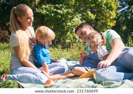 Portrait of happy young family consisted of mom daddy son and little daughter laughing having a picnic