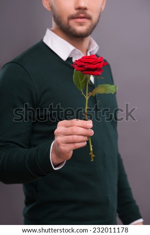 Selective focus on the beautiful red rose wonderful gift for lover in the hands of the man on background