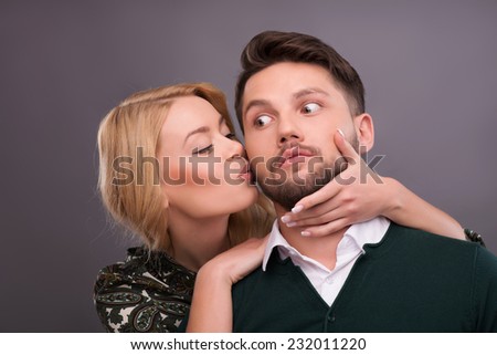 Half-length portrait of beautiful smiling blonde hugging her boyfriend showing her love wanted to kiss him. Isolated on dark background