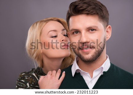 Half-length portrait of beautiful smiling blonde hugging her boyfriend showing her love wanted to kiss him. Isolated on dark background