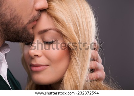 Half-length portrait of lovely happy smiling couple standing with closed eyes facing each other enjoying the moment they are together