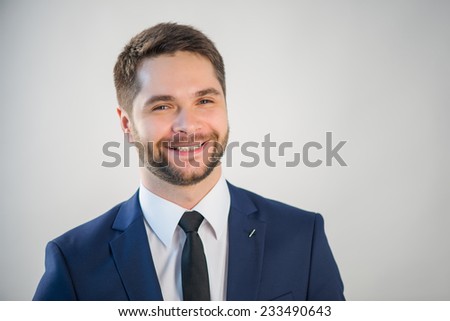 Half-length portrait of handsome young bearded smiling man wearing white shirt tie and blue jacket. Isolated on white background