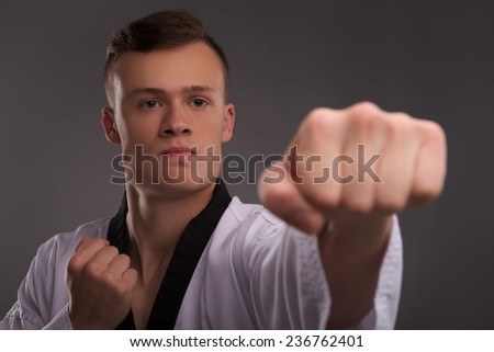 Selective focus on the young handsome fair-haired karate enthusiast wearing white kimono coaching himself before the important fight