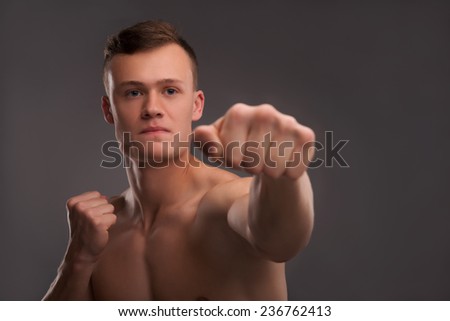 Selective focus on the young handsome fair-haired bare-chested karate enthusiast coaching himself before the important fight