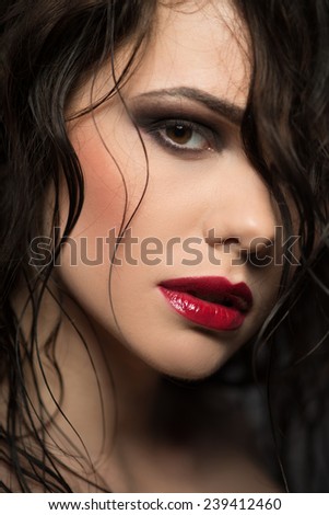 Selective focus on the beautiful sexy dark-haired woman with great evening make- up looking at us seductively