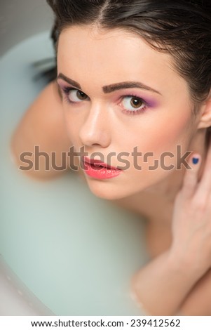 Half-length portrait of beautiful sexy dark-haired woman lying in the bath looking at us wanted to ask something