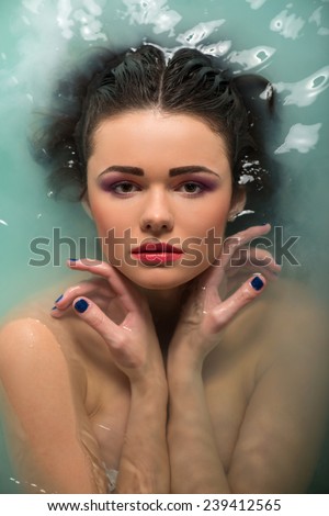Half-length portrait of beautiful sexy dark-haired woman lying in the bath looking at us thinking about something enjoying this moment. Top view