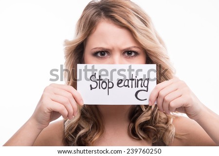 Closeup portrait of young attractive woman holding prohibition card with stop eating notice isolated on white background, diet concept