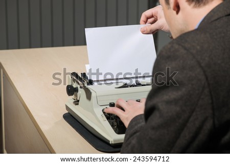 Working at the typewriter. Close-up of blank paper for copy space and the man is typing something on typewriter
