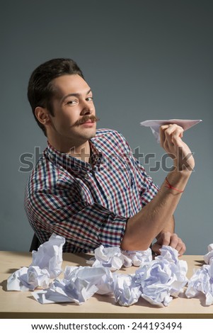 In search of inspiration. Close-up of author throwing paper planes while sitting against grey background