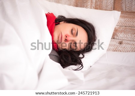 Feeling unwell. Closeup image of young sick woman sleeping in bed with sore throat in scarf
