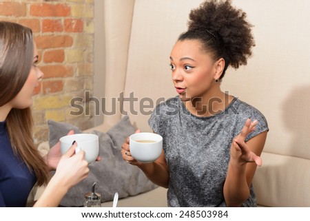 Two friends in cafe. Two young female friends sitting in cafe and talking to each other on the brick wall background