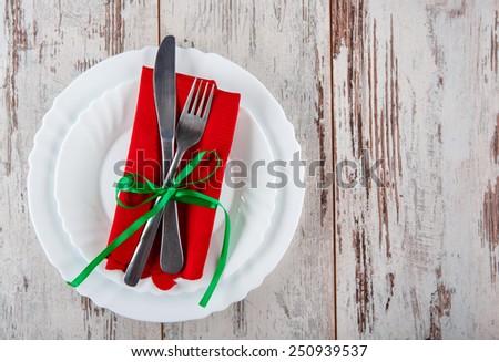 Celebrating a special moment. Closeup of elegant table layout and cutlery with red napkin and green stripe served on wooden table