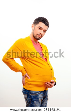 It is not easy to expect. Funny conceptual photo of gender reversal when a pregnant man with a belly holding his waist by his hand while posing isolated on white background