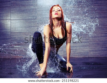 Dancing is her passion. Portrait of beautiful young contemporary dancer dancing under the water shower while standing against black background
