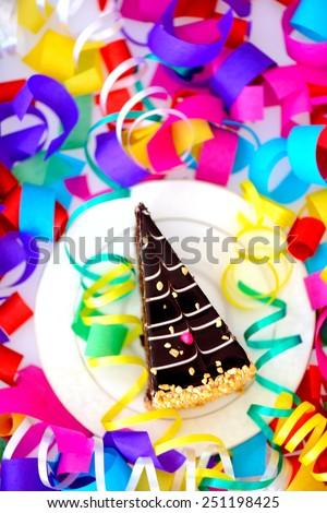 Birthday cake. Closeup top view of a piece of chocolate cake with a birthday candle decorated with confetti isolated in white background