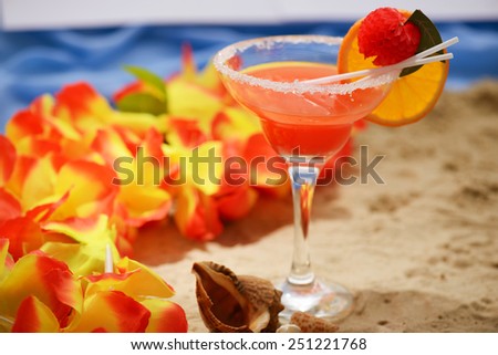 Ready to relax. Image of summer fruit cocktail surrounded by exotic flowers and sea shells with stripe of water on the background