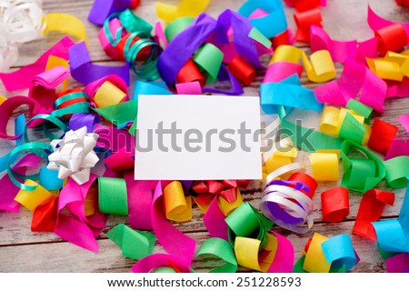 With best wishes. Closeup image of a blank greeting card with copy space in the pile of multicolored confetti on wooden background