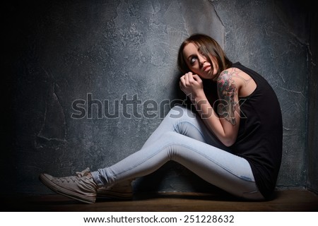 Feeling hopeless. Young woman trapped looking up while sitting on the floor in a dark room