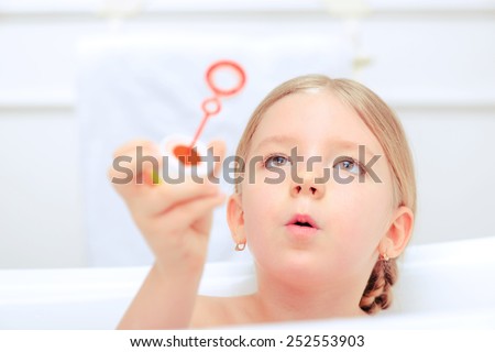 Happy days of childhood. Cropped image of a cute little girl taking a bath and playing with soap bubbles while sitting in a luxurious bathtub