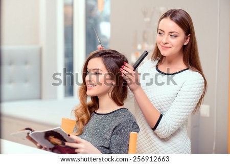 Going for a change of style. Young beautiful woman discussing hairstyling with her hairdresser holding a comb and scissors while sitting in the hairdressing salon