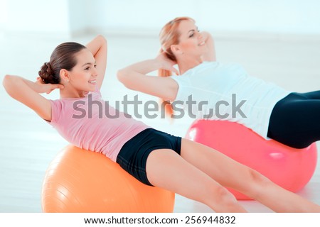 Fitness every day. Closeup side view image of beautiful teenage girl and her mother in sports clothing training on fitness balls in sports club