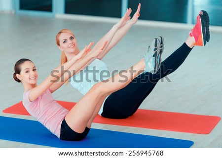 Fit for life. Top view of beautiful teenage girl and her mother in sports clothing training yoga and taking similar positions on the mat in sports club