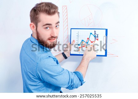 Targeting the consumers. Rear view with selective focus of young handsome man in smart casual wear pointing at marketing chart on the board while having a brainstorming