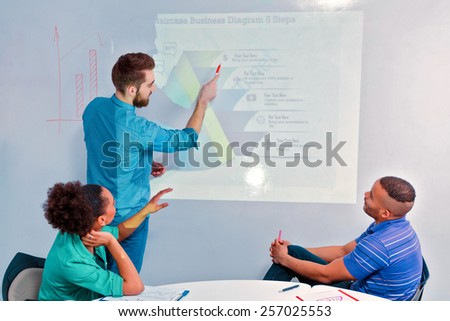 Creative brainstorming. Rear view of group of cheerful business people in smart casual wear discussing infographics and writing on the board in the meeting room