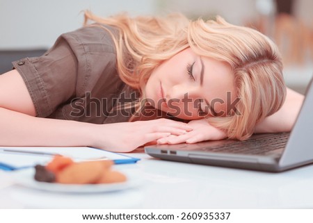 Sleeping at working place. Attractive young woman sleeping at her working place on the laptop