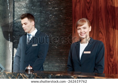 Best service at your disposal. Two good-looking receptionists in uniform welcome guests with a smile standing behind the reception desk
