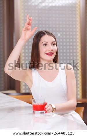 Meeting with a friend. Beautiful smiling brunette waves with a hand to someone at the counter of the bar