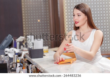 Let the party start. Beautiful woman ready to order something for a drink raises a hand to call a barman