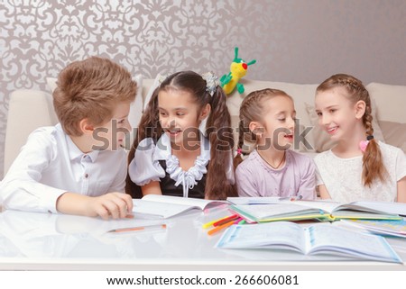Curious talks. Four schoolkids talking in pairs sitting at the table in a living room