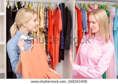 Better do not. Saleswoman in a retail store showing with a gesture to the female customer that the dress does not fit her