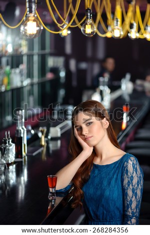 So bored. Young woman obviously bored and tired sitting by the bar counter with cocktail