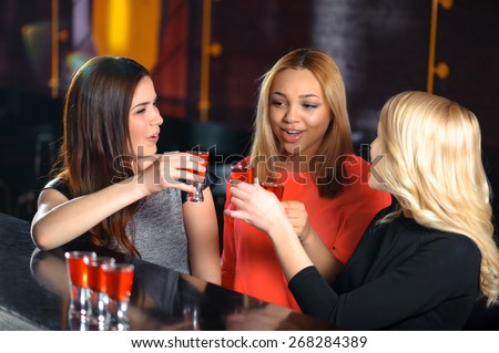Cheers to friendship. Three beautiful women entertaining in the bar and toasting shots