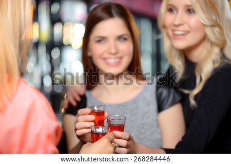 Cheers to friendship. Three beautiful women entertaining in the bar and toasting shots