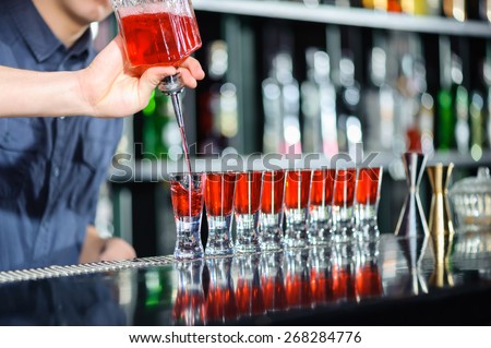Excitement. Close-up of barman hand pouring alcohol into shot glasses in a nightclub or bar