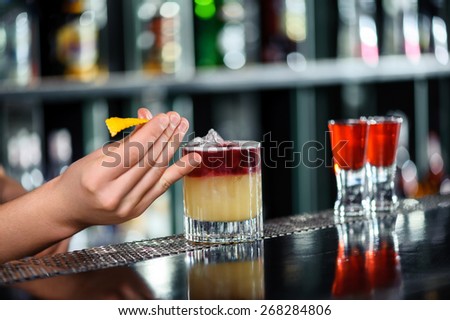 Stylish decoration. Close-up of a bartender placing a slice of citron onto the cocktail in a glass