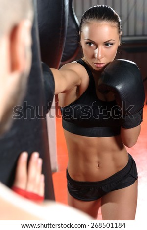 Strong jab. Young beautiful woman boxer kicking a punching bag with a jab