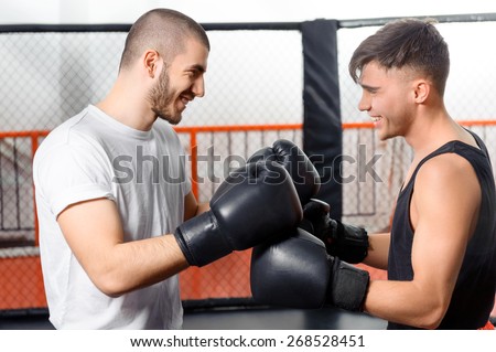 Friendly game. Two boxers joyfully laugh standing in a fighting cage