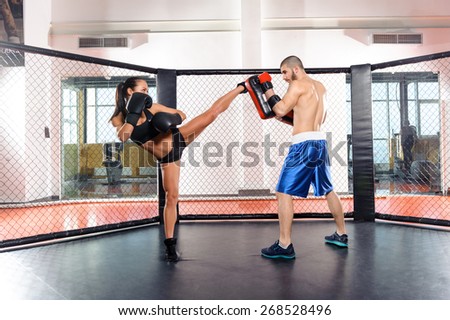 Female box. Training session of a female fighter kicking a punching pad held by a couch