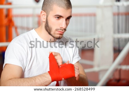 Kickboxer. Close up of a young sportsman applying boxing bandage in a boxing ring