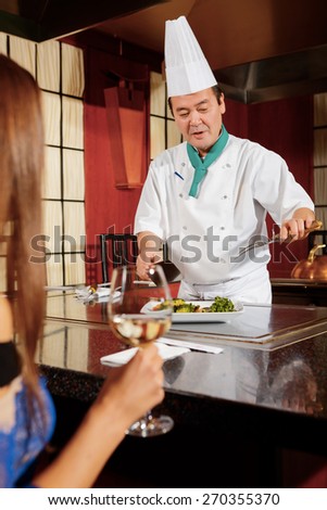 Nice talk. Asian cook telling a female guest about the meal he is serving