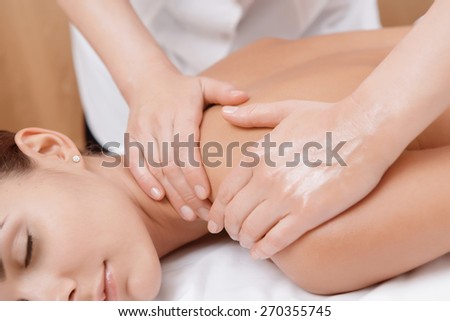 Healthy body. Close-up of female hands giving massage with oil to a young brunette in spa salon