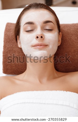 Close-up of a young brunette peacefully relaxing with a beauty mask on her face in a beauty parlor
