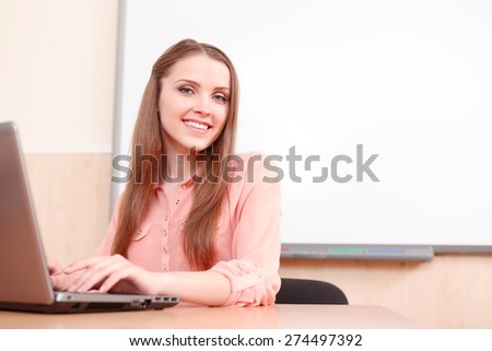 Online work. Beautiful young woman working on computer on background of white blackboard.
