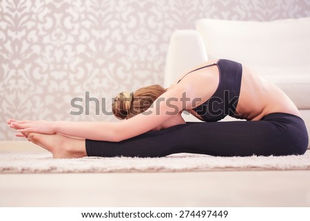 Push yourself. .Young woman doing stretching exercises by pushing forward her body to her legs.